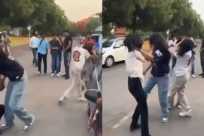Four girls fight in the middle of the road.  Policeman as a spectator